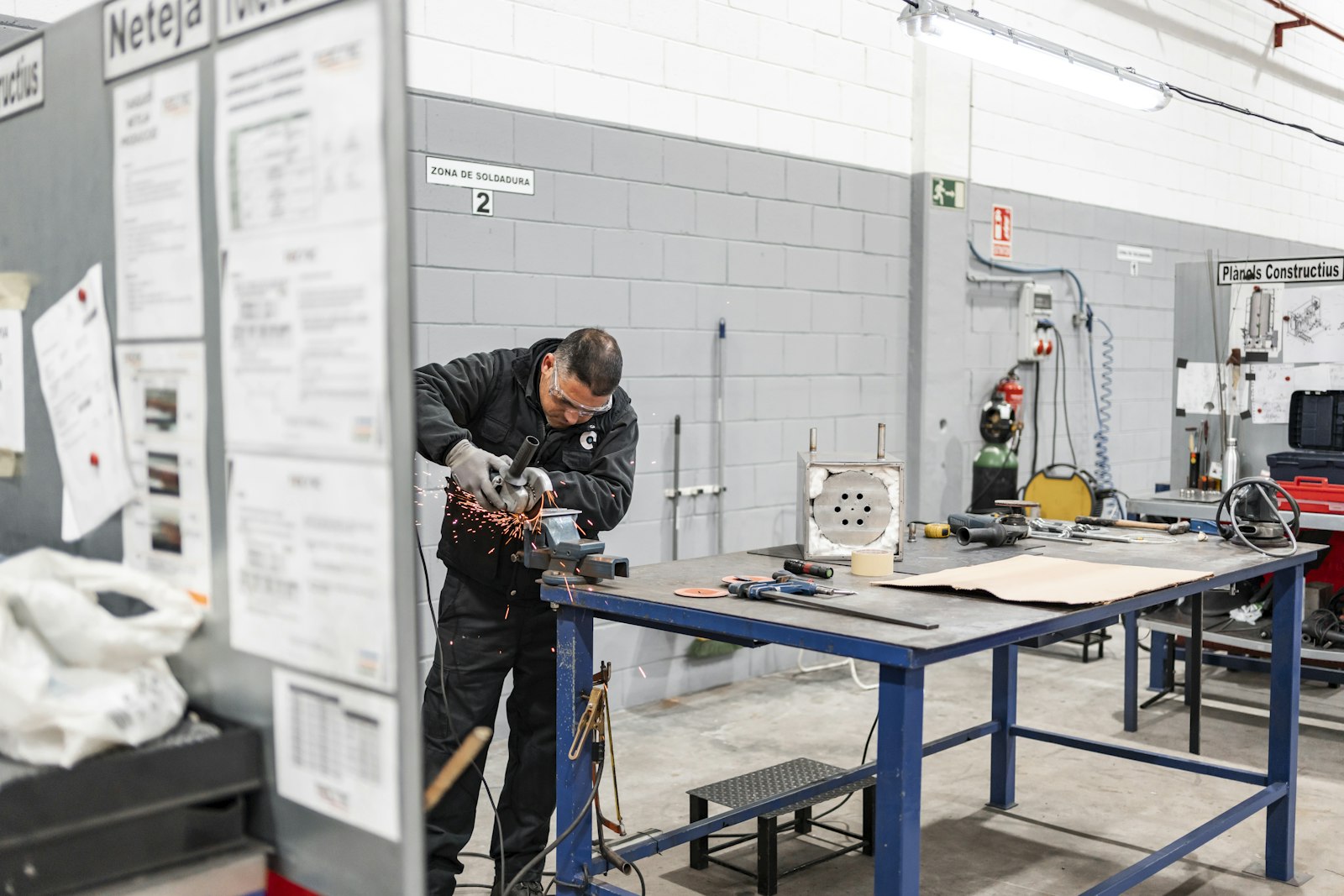 A trainee grinding metal in a workshop