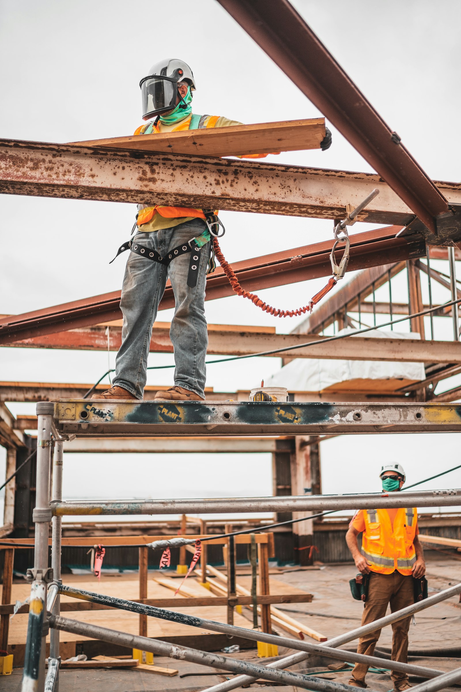 A construction worker on scaffolding near steel beams