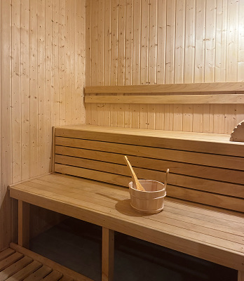 Drewniane wiadro z uchwytem ustawione na drewnianej ławce w saunie.