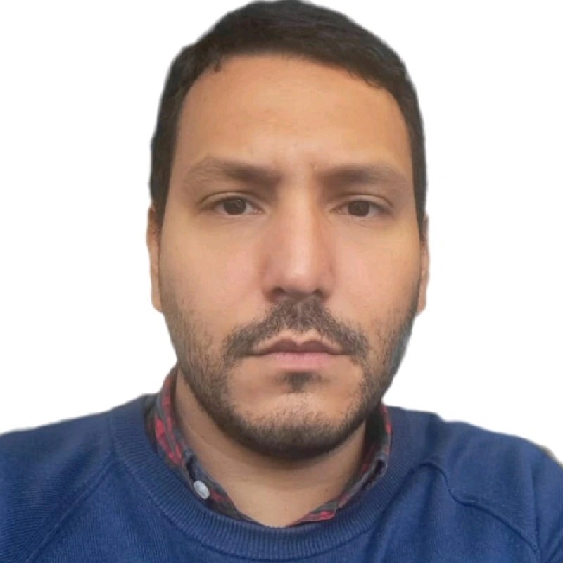 Žena s hnědými vlasy se usmívá venku, v pozadí jsou stromy a žluté listí.