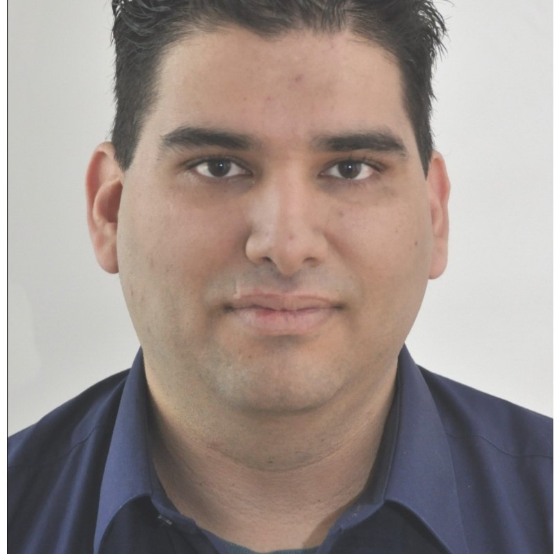 Žena s hnědými vlasy se usmívá venku, v pozadí jsou stromy a žluté listí.