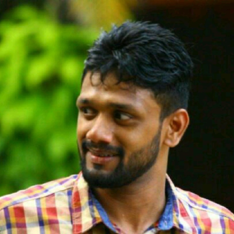 Žena s hnědými vlasy se usmívá venku, v pozadí jsou stromy a žluté listí.