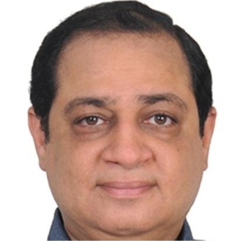 Žena s hnědými vlasy se usmívá venku, v pozadí jsou stromy a žluté listí.