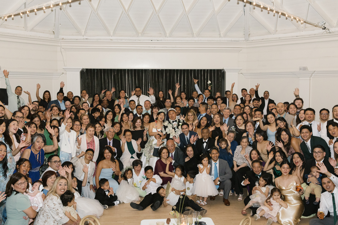 Bride, groom, and wedding party smile for the camera on the dance floor.