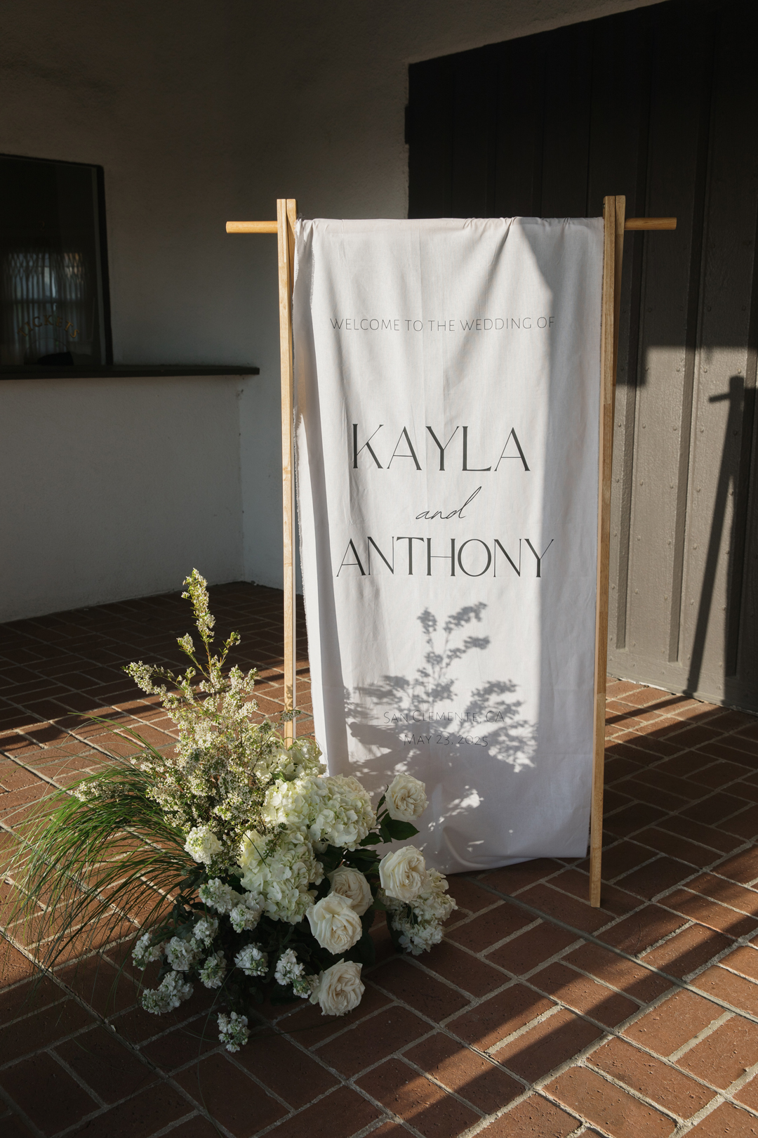 White linen wedding welcome sign hangs at The Casino San Clemente wedding venue entrance.