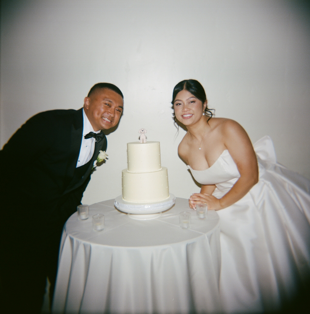 Bride and groom smiling with their wedding cake.