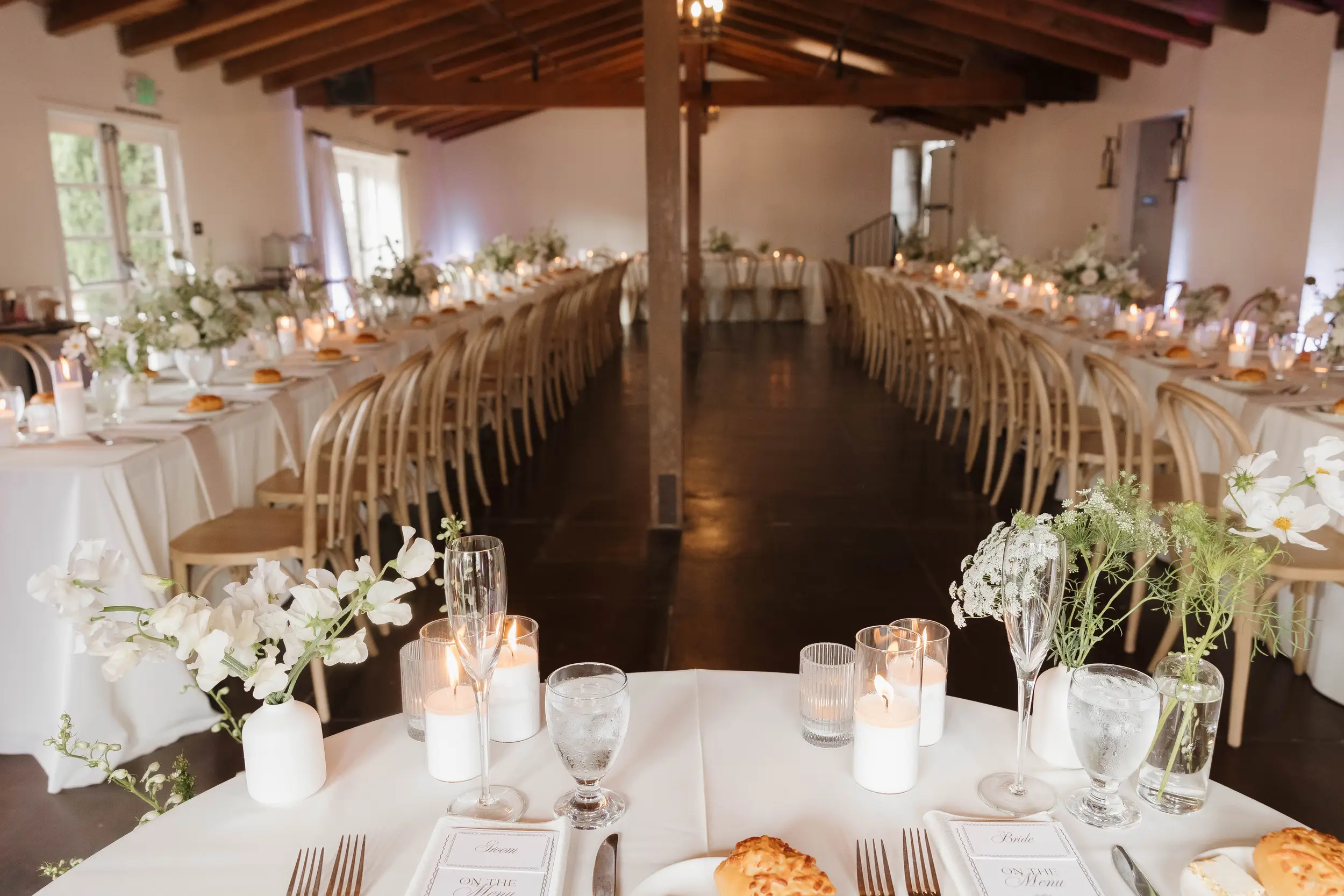ivory floral centerpieces top reception tables inside the Casino San Clemente's West Wing for a wedding reception.