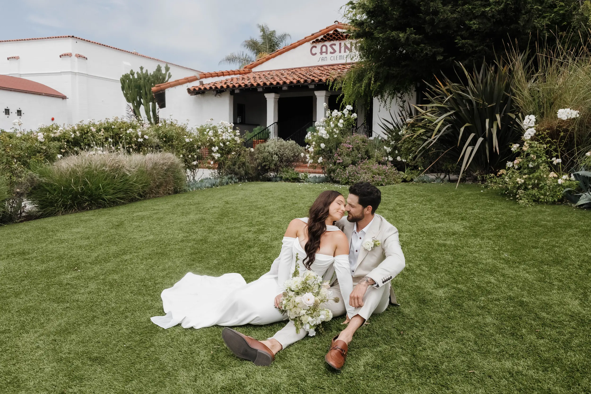 Bride and groom cozy up on the front lawn at the Casino San Clemente for photos.