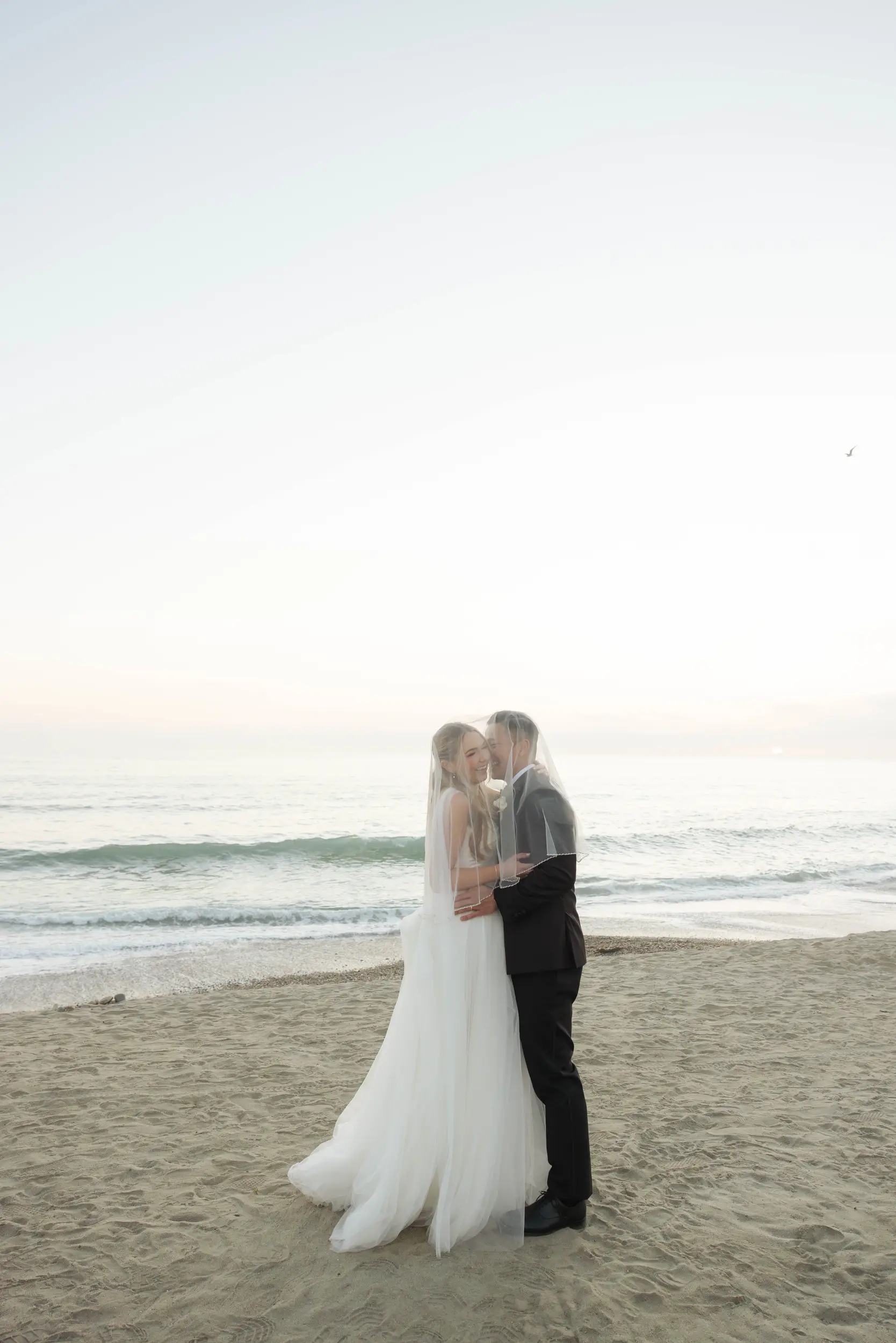 Bride and groom pose for sunset romantics on the beach during cocktail hour.