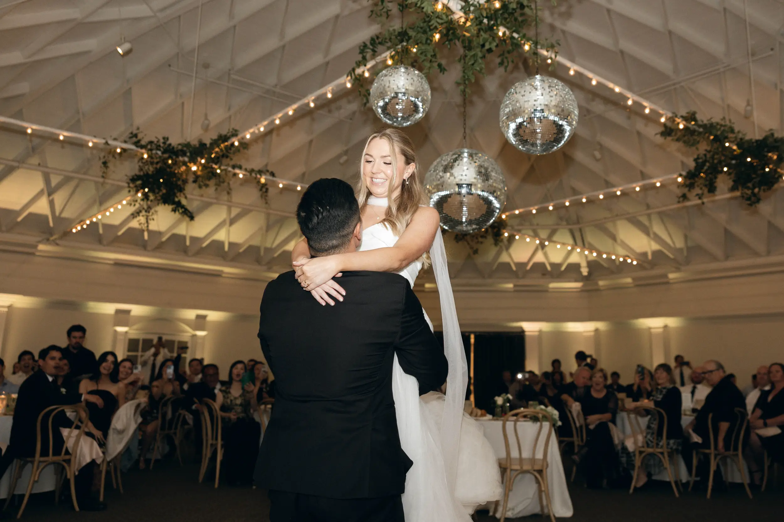 Bride and groom share first dance out on the dance floor under disco balls.