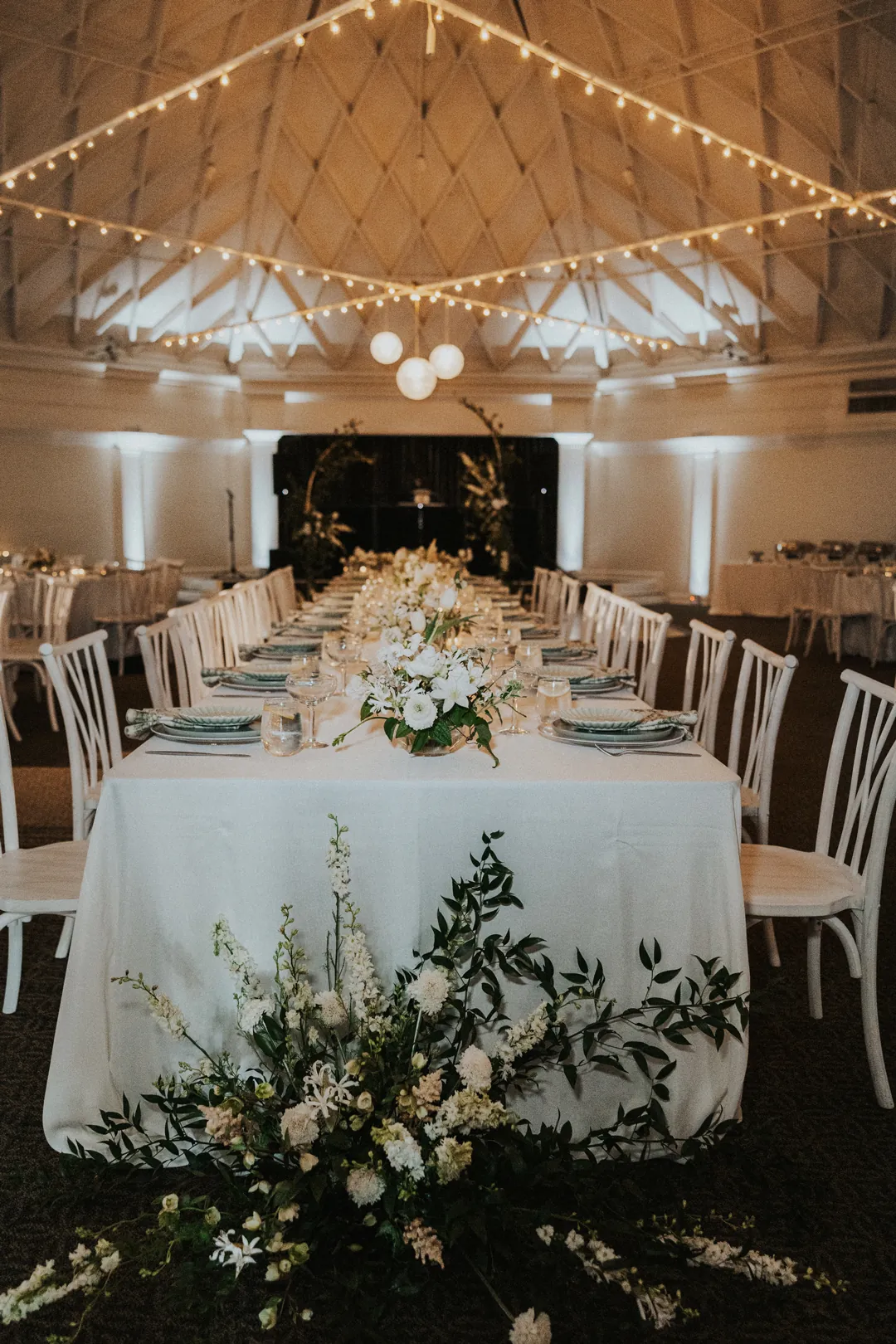 Sage, mint, and white top reception tables inside the Casino San Clemente.