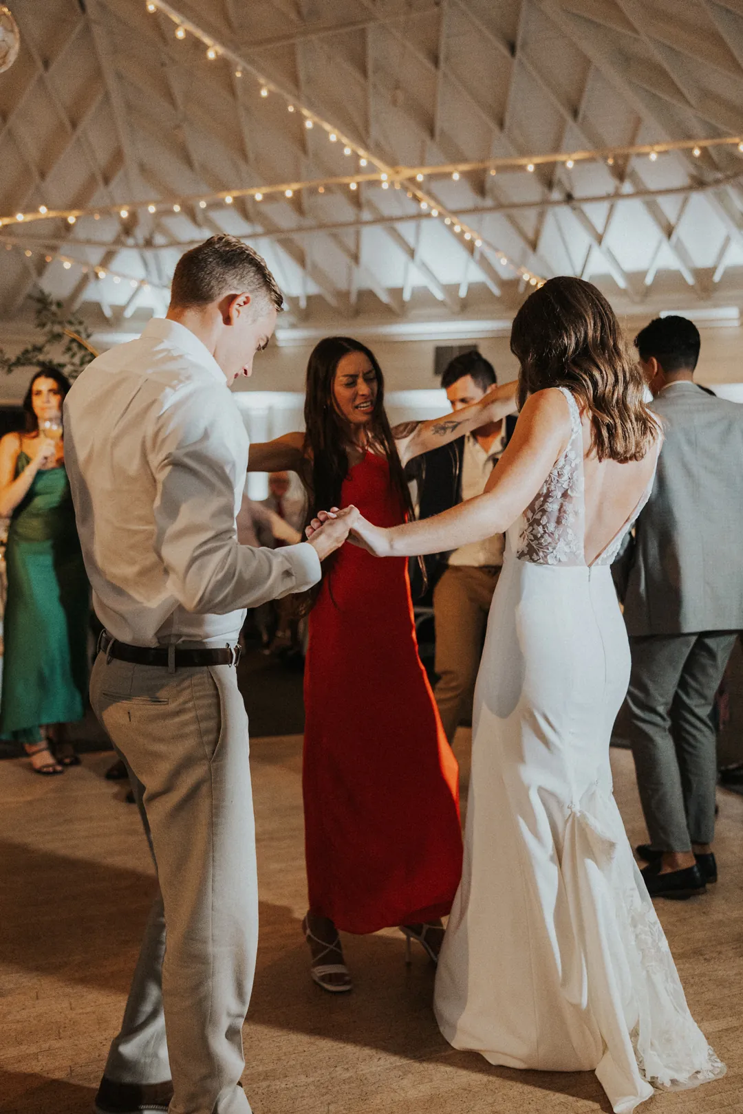 Bride and groom dance with a friend out on the dance floor.