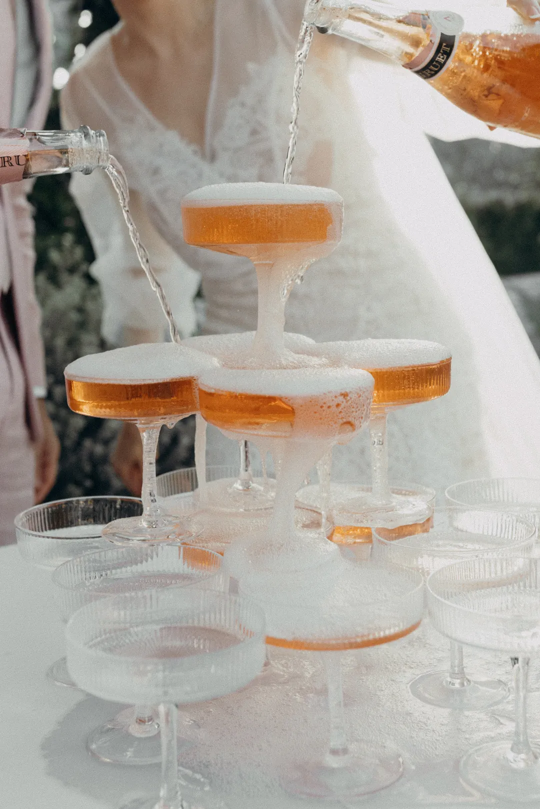 Bride pours champagne into champagne tower.