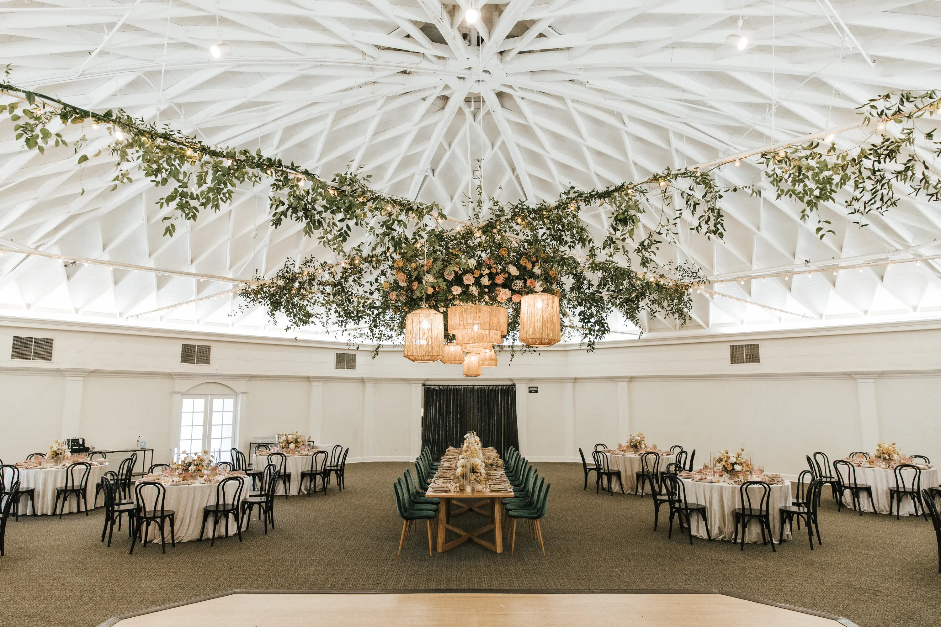 Grand Ballroom reception tables beneath hanging greenery, peach flowers, and woven pendant lights.