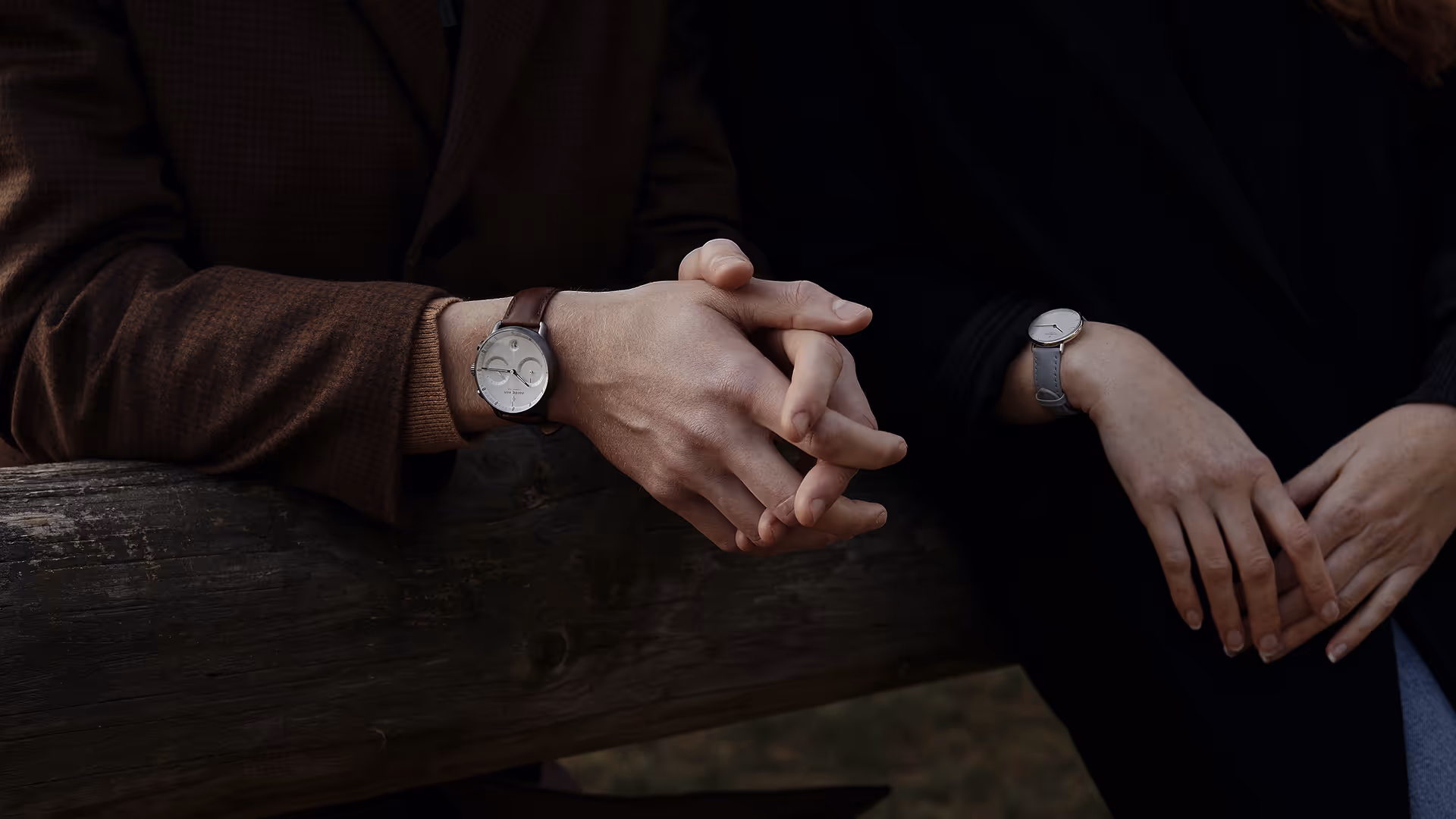 Mains entrelacées avec montres élégantes sur fond sombre