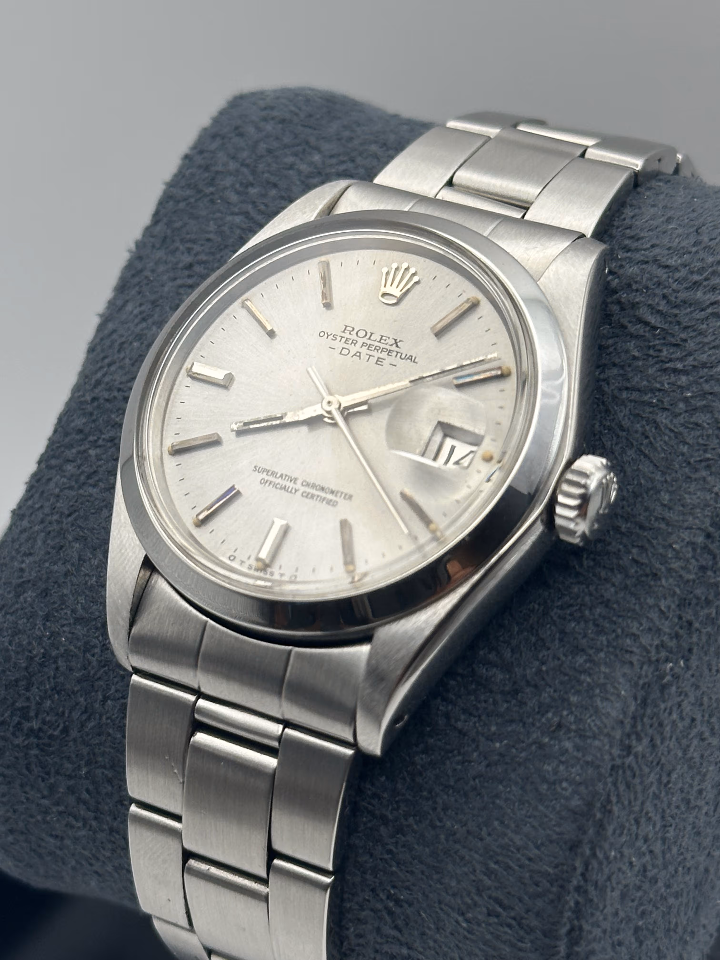Très belle et extrêmement rare Rolex Oyster Perpetual Date ref. 1500 de 1974, proposée ici en full set avec sa boîte d’origine et surboîte, un ensemble particulièrement recherché par les collectionneurs. Cette pièce se distingue par son élégant cadran argent à signature sigma, attestant de la présence d’index appliqués en or blanc, accompagnés de plots tritium d’époque offrant une patine subtile et homogène. Son boîtier Oyster de 34 mm, aux proportions intemporelles, est complété par un bracelet Rolex d’origine en configuration full links, garantissant un ajustement optimal. Révisée en mars 2026, cette montre allie authenticité, fiabilité et charme vintage, représentant une opportunité rare d’acquérir un modèle emblématique dans un état et une configuration aussi complets.