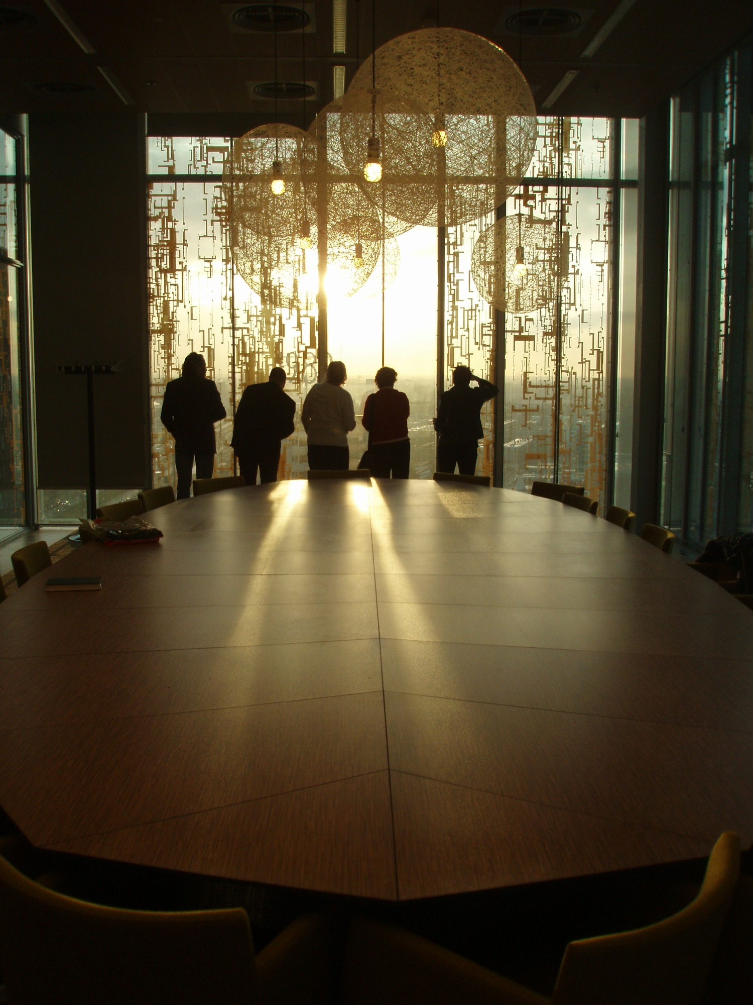 People silhouetted at a boardroom window in golden evening light
