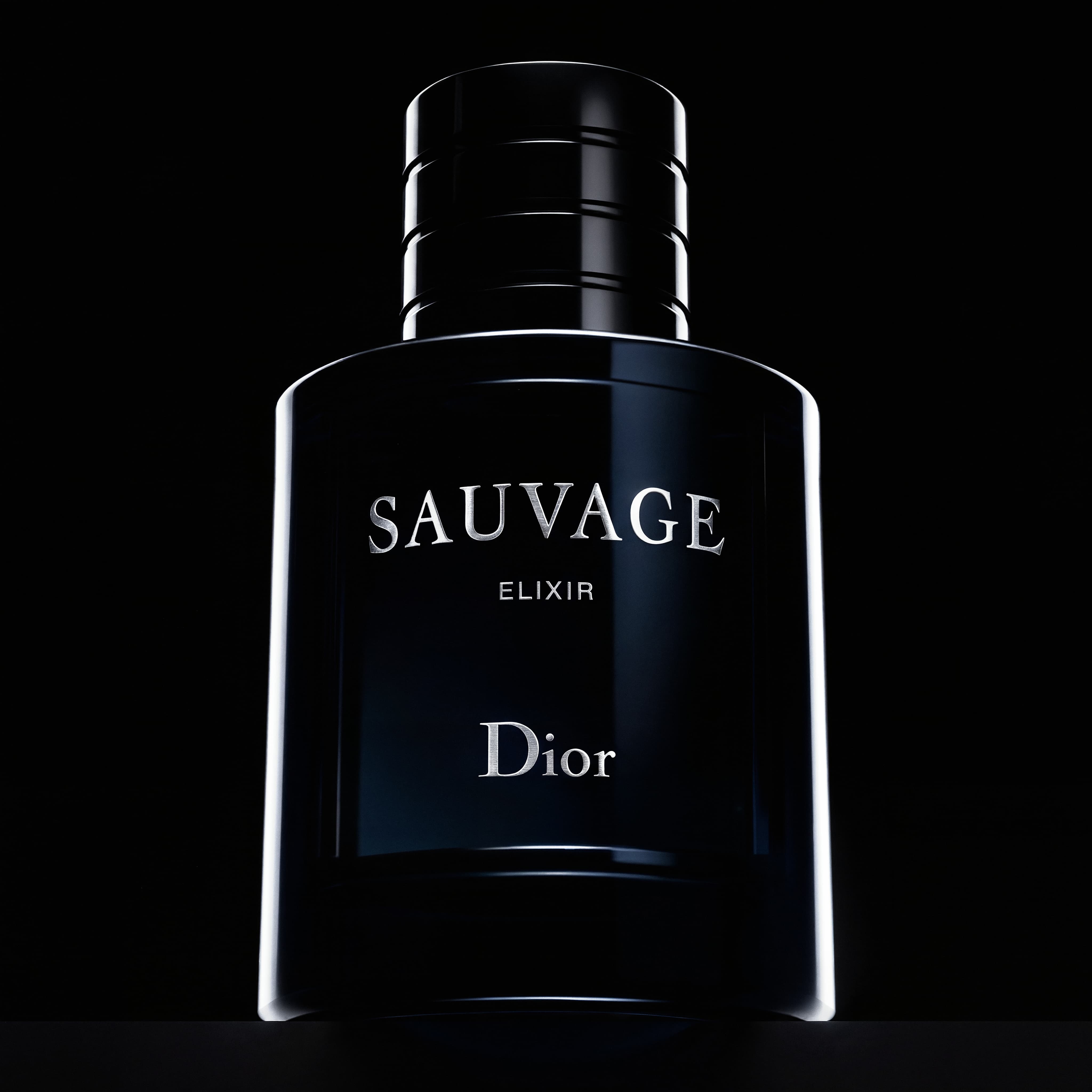 Close-up of a black Dior Sauvage Elixir perfume bottle against a dark background.
