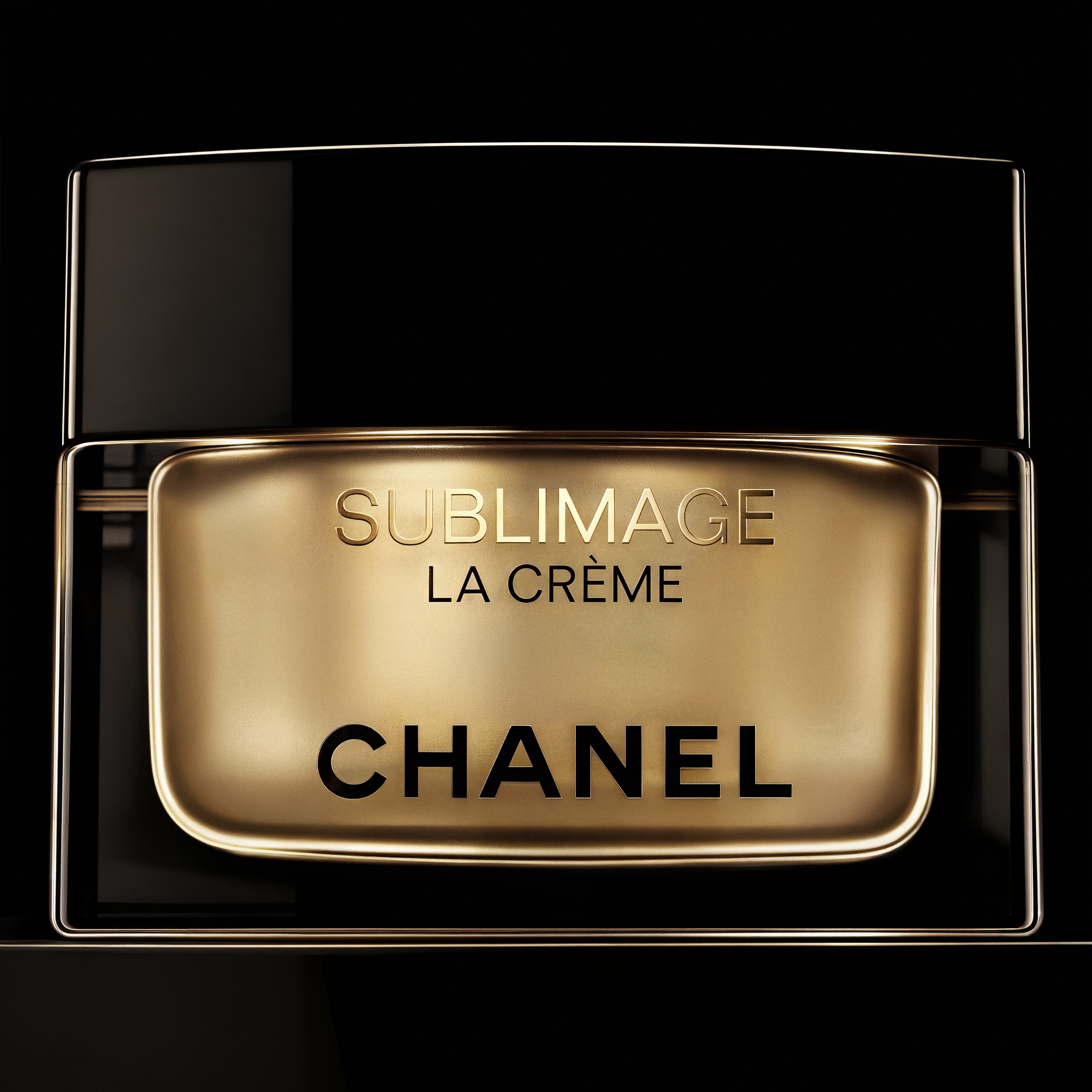 Close-up of a gold and black Chanel Sublimage La Crème cosmetic jar against a black background.