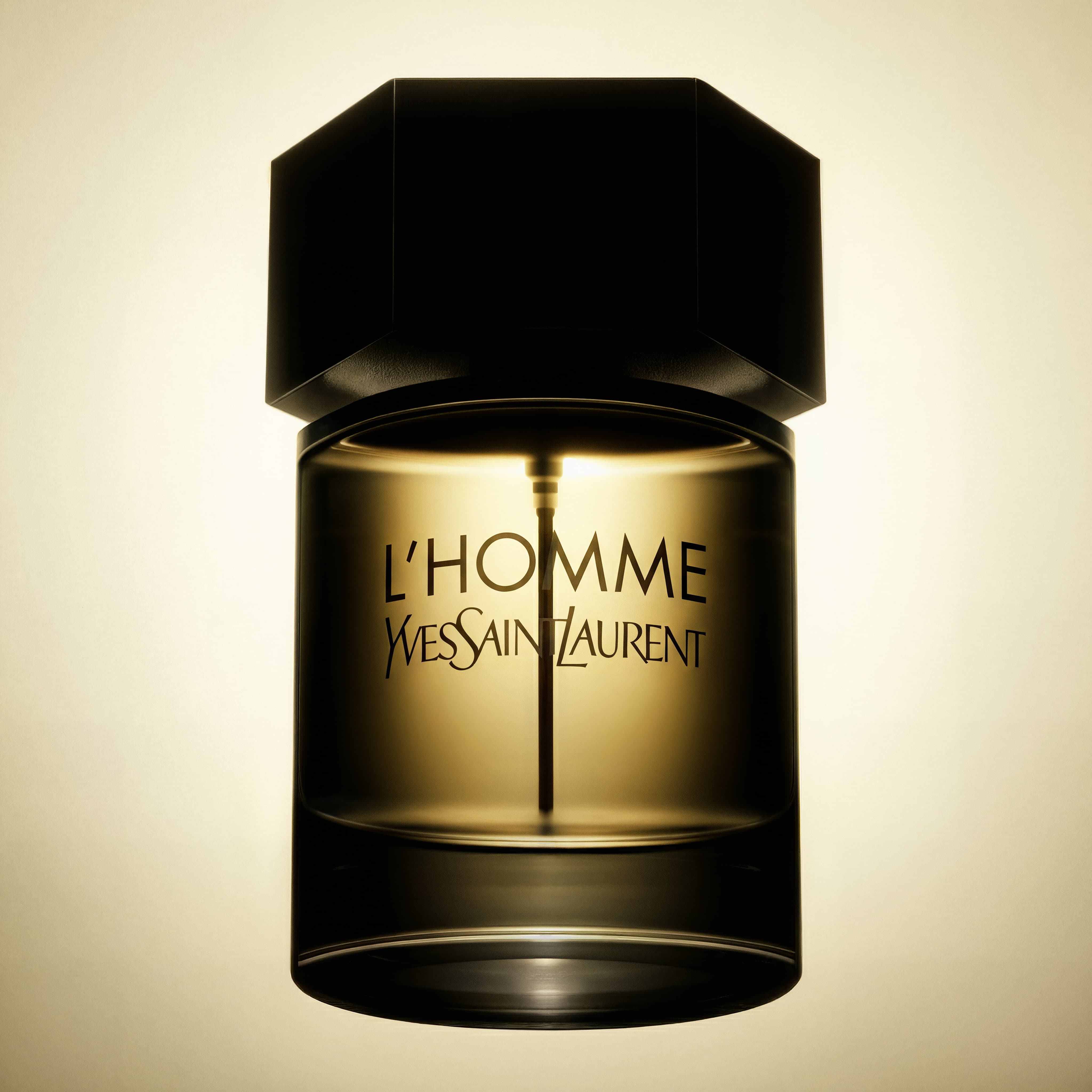 Close-up of a transparent cylindrical Yves Saint Laurent L'Homme perfume bottle with a black hexagonal cap.