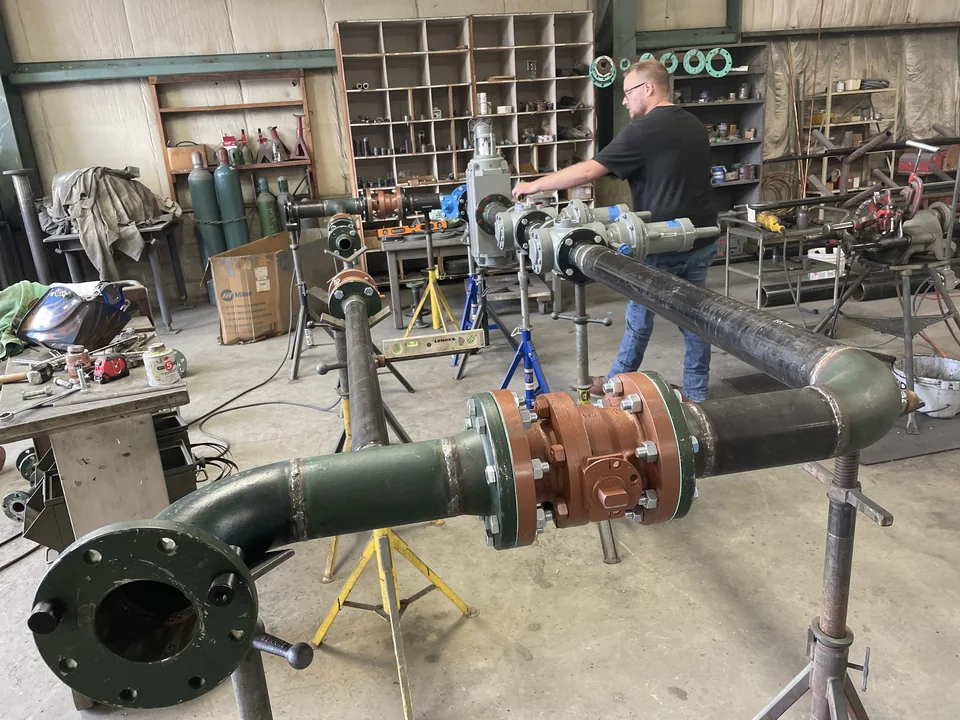 JNL Fab technician assembling a district regulator station on pipe stands in the fabrication shop.