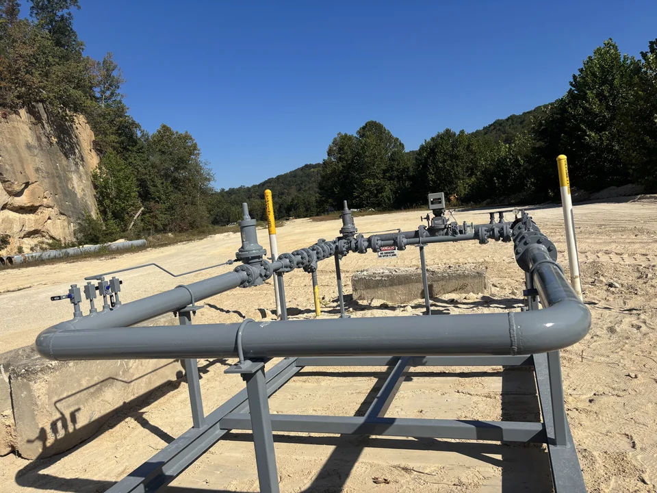 High-capacity natural gas regulator station with vent stacks on a steel skid, installed on a gravel pad.
