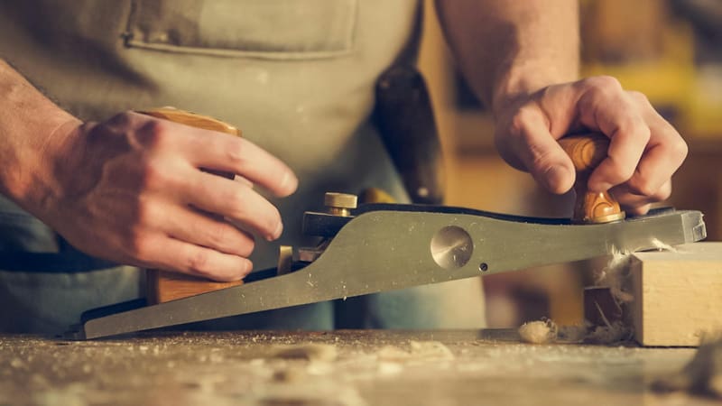 Handwerker nutzt eine Hobelmaschine, um Holz glatt zu ziehen.