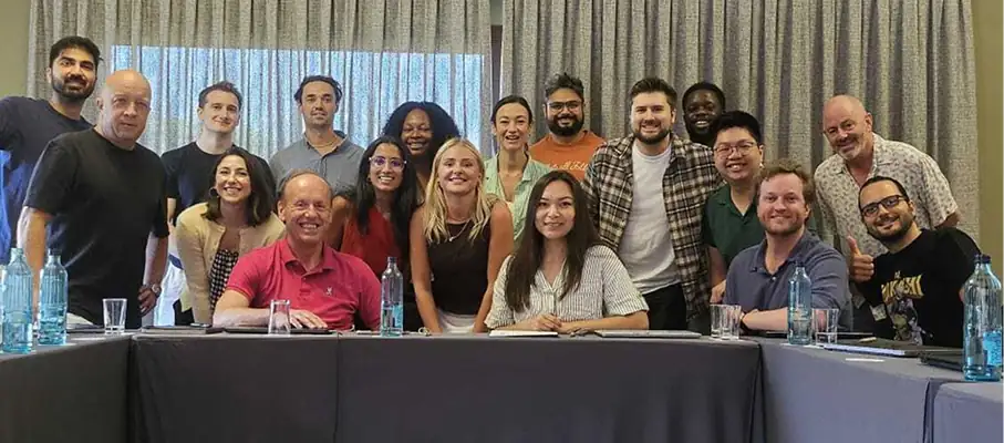 Large diverse group of people smiling together at a conference table with water bottles.