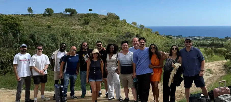 Group of people posing together on hillside overlooking Mediterranean coastline