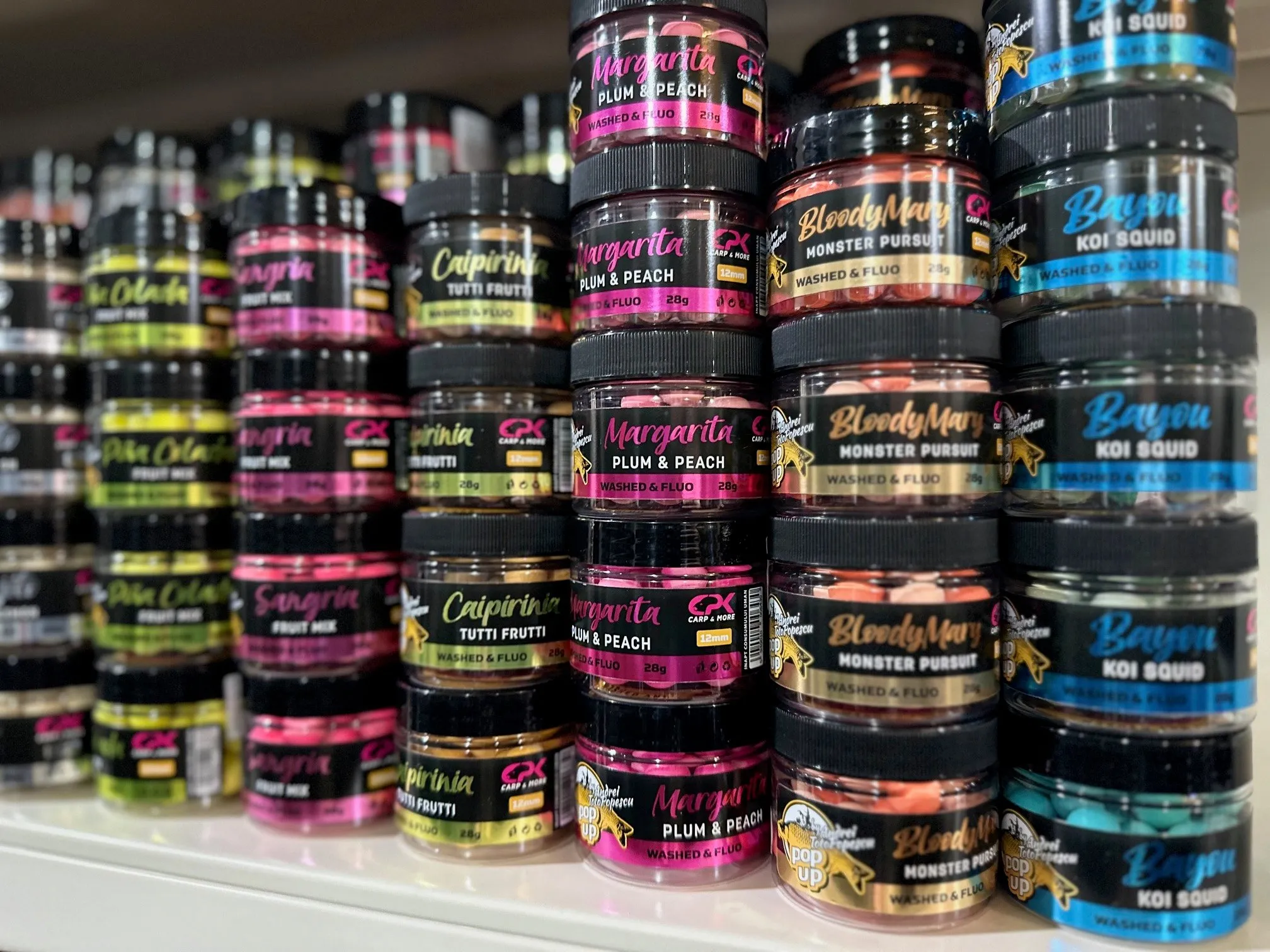 Regal mit Reihen stapelbarer Dosen verschiedener Aromen wie Margarita Plum & Peach, Caipirinha Tutti Frutti, Bloody Mary Monster Pursuit und Bayou Koi Squid.