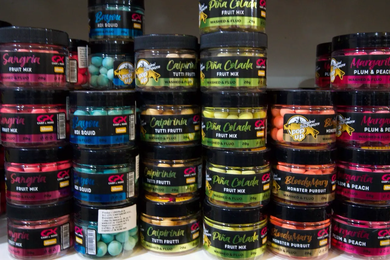 Mehrere Reihen bunter Köderbehälter mit verschiedenen Geschmacksrichtungen wie Sangria, Koi Squid, Caipirinha, Piña Colada, Bloody Mary und Margarita.