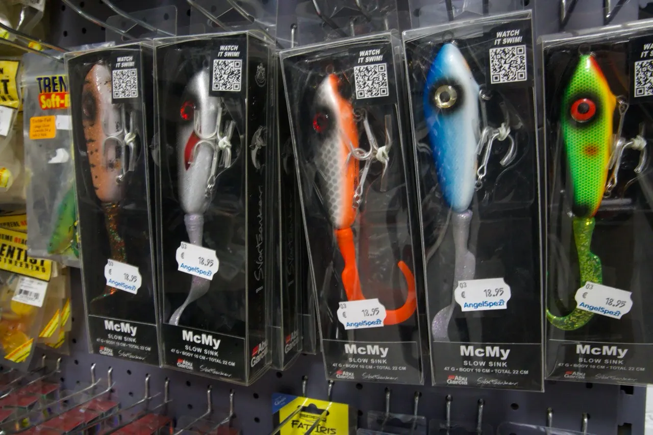 Mehrere McMy Slow Sink Angelköder in verschiedenen Farben in Verpackungen an einem Ladenregal.