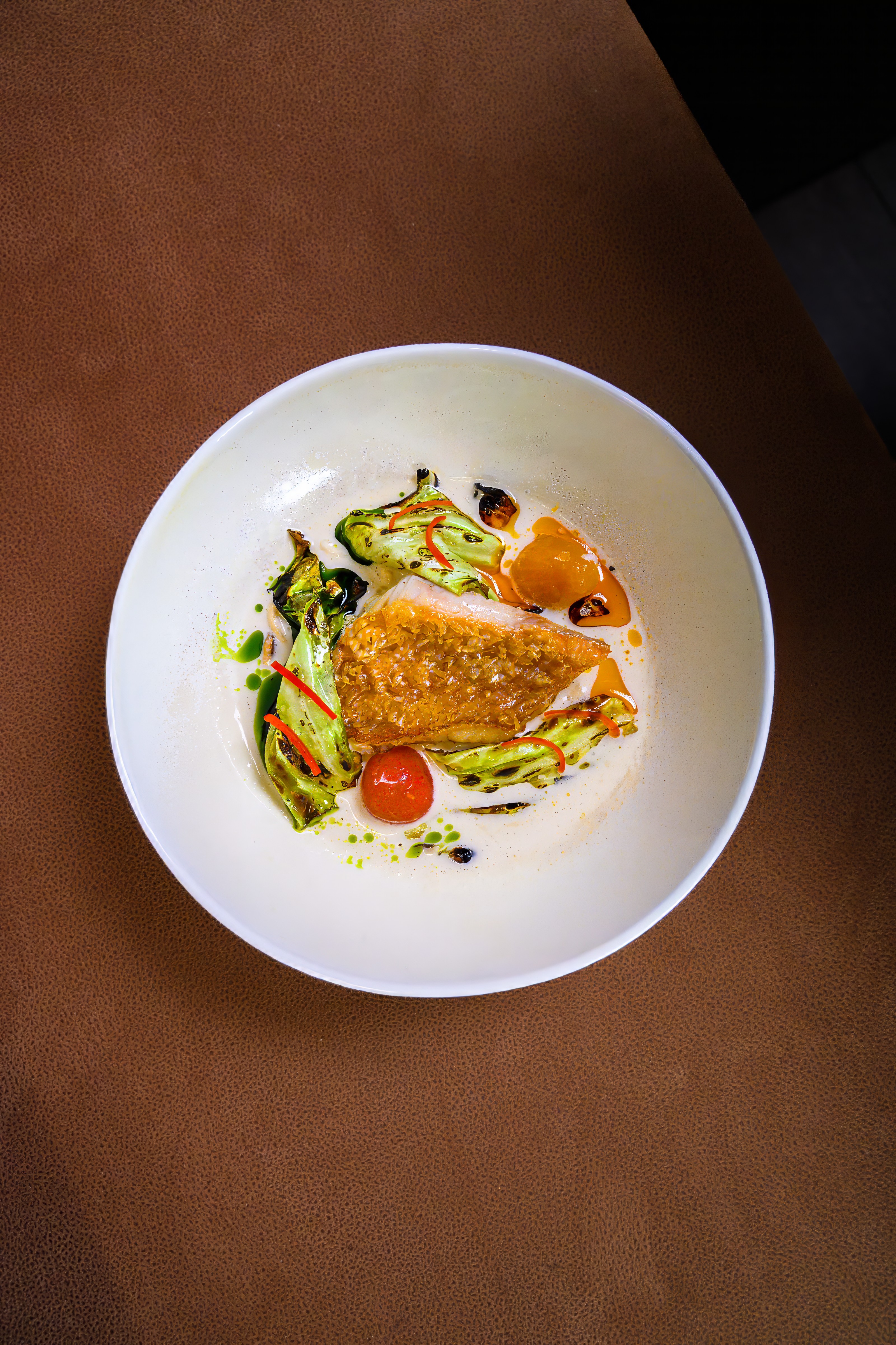 A composed restaurant dish photographed on a warm leather table