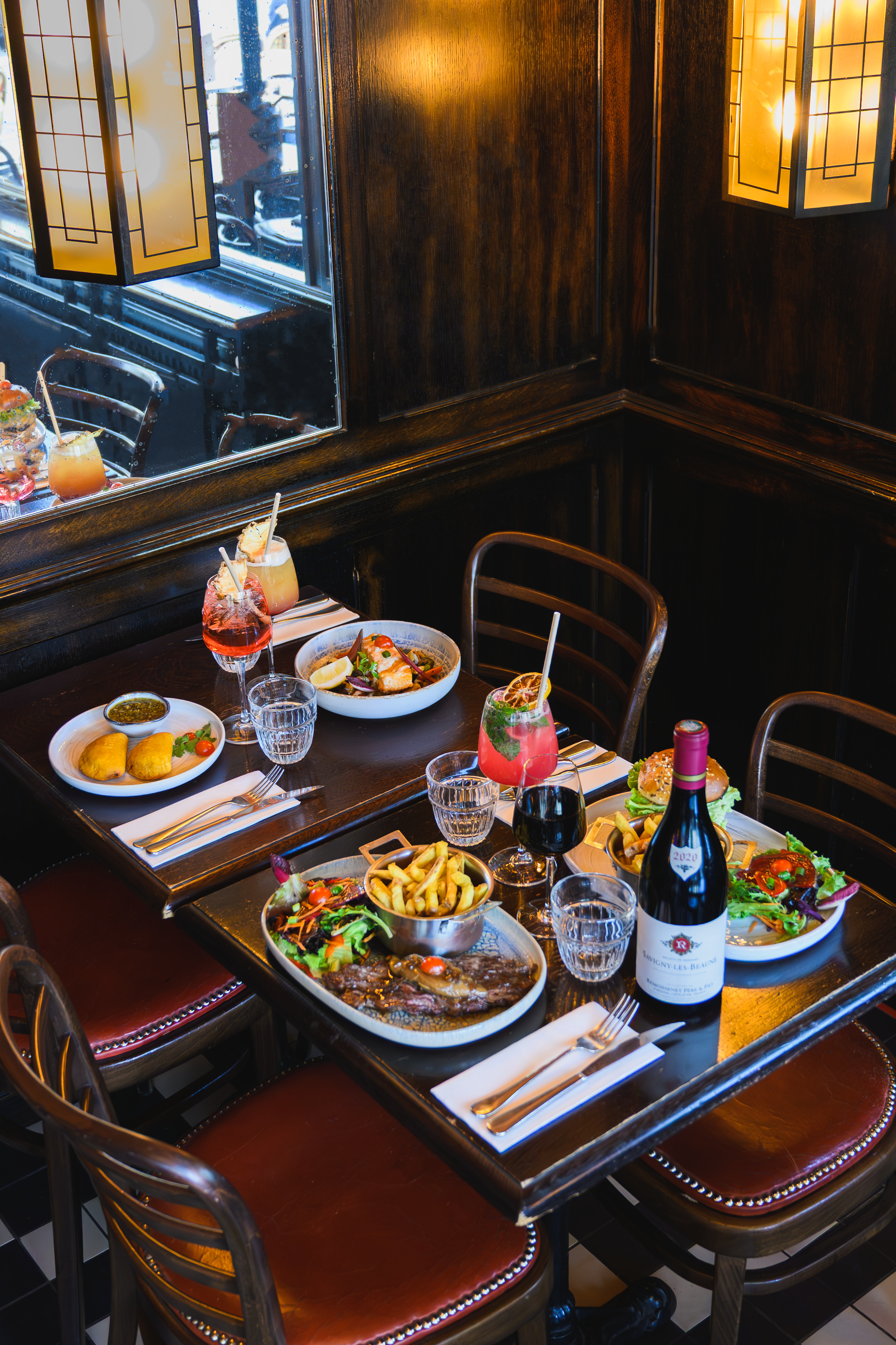 A fully set restaurant table with food, wine and cocktails