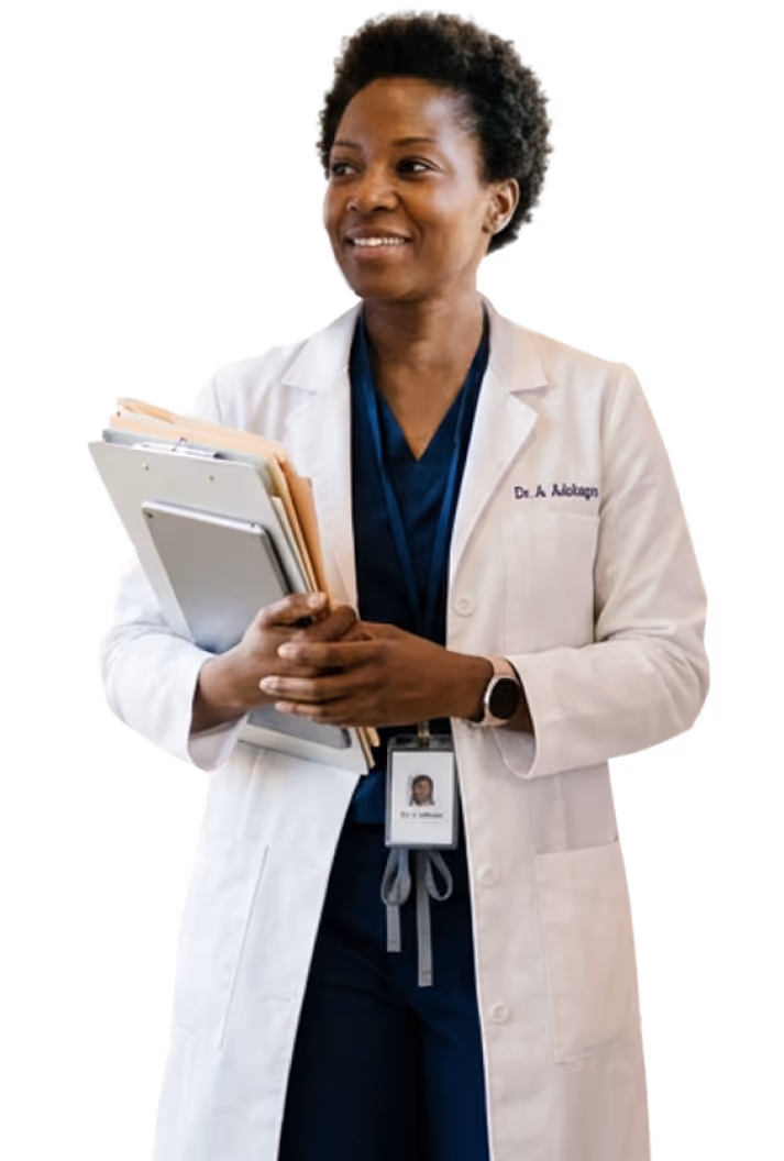 Female doctor in white lab coat holding folders and a tablet, smiling and looking to the side.