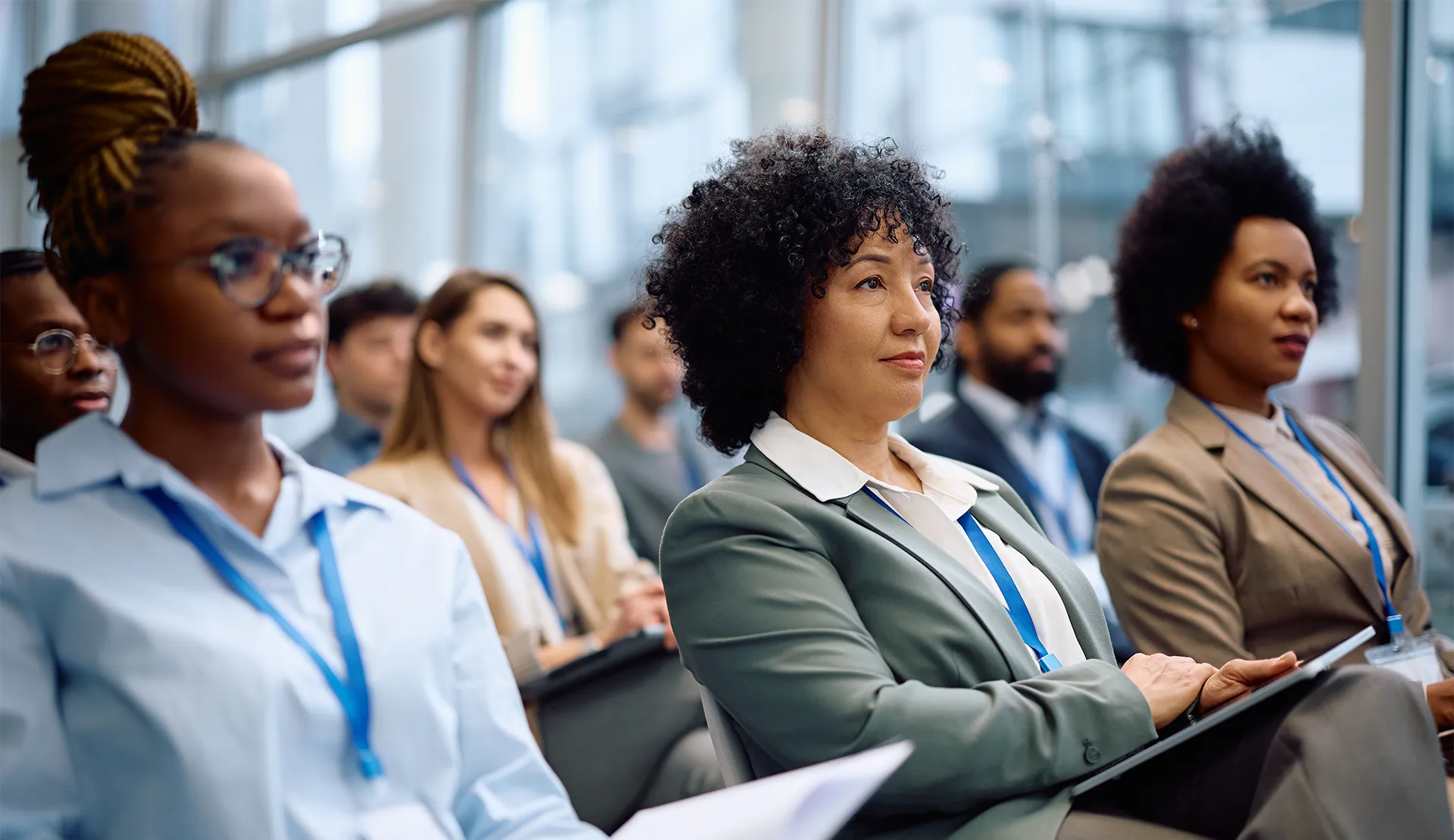Diverse group of professional adults attentively listening in a modern conference room.