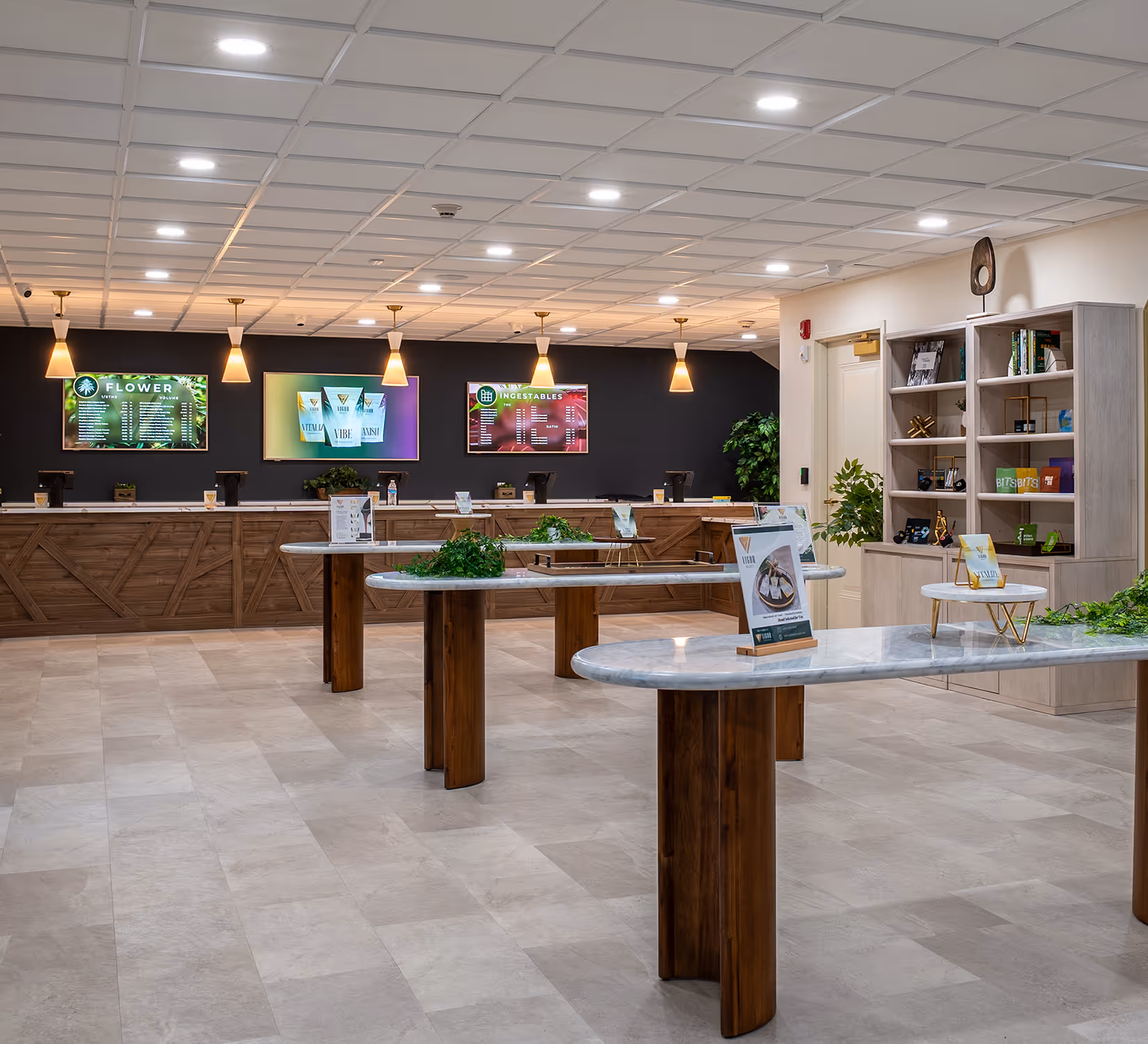 Modern dispensary interior with marble tables, digital menu boards, and wooden cabinetry under pendant lights.