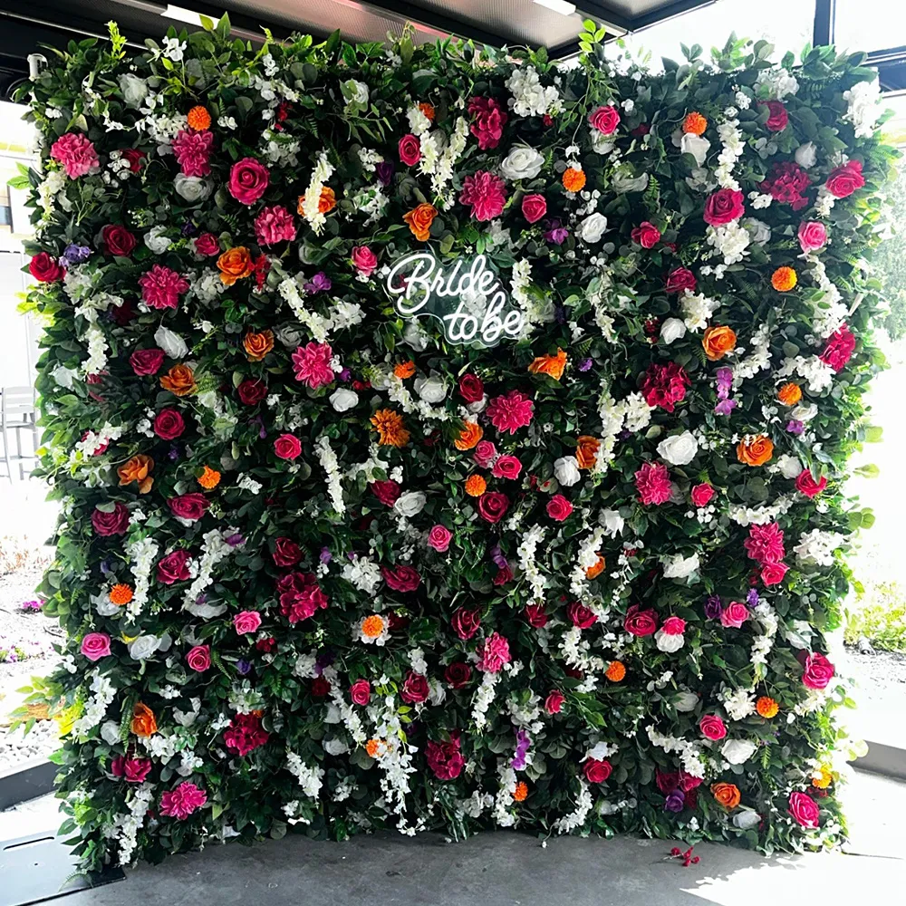 Floral backdrop with dense greenery and colorful flowers including roses, decorated with a white 'Bride to be' sign in the center.