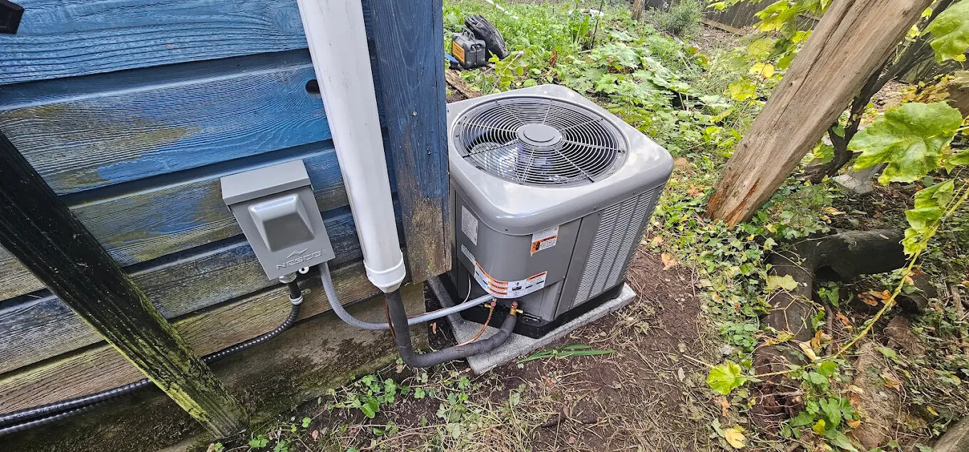 A modern exterior air-source heat pump unit installed on a concrete pad next to a residential home's siding.