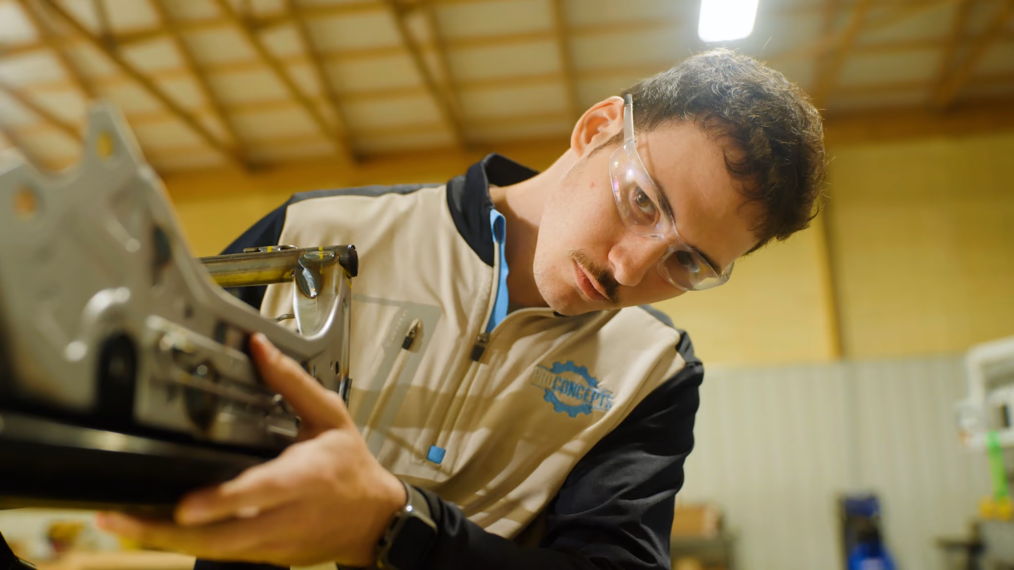 ProConcepts team member wearing safety glasses inspecting a metal fixture part