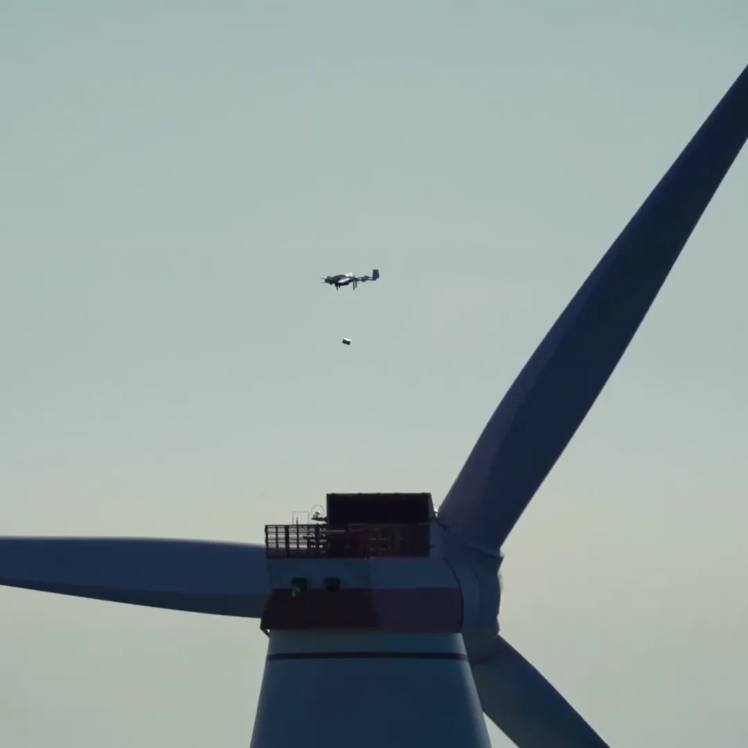 Single offshore wind turbine standing in the sea under a clear blue sky.