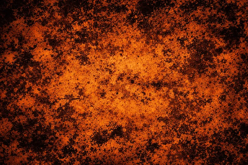 Rusty orange and black textured surface resembling corroded metal.