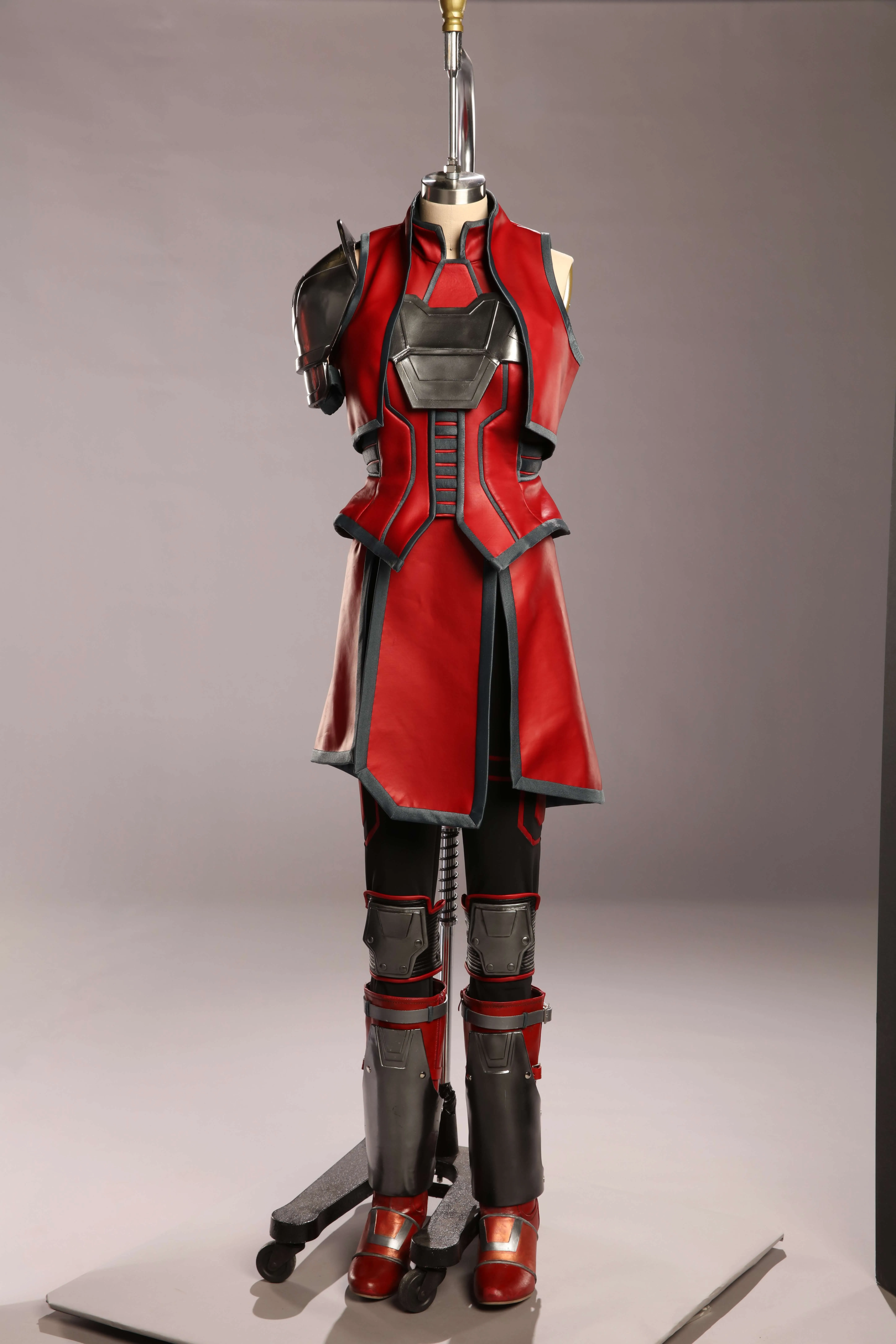 Red and black futuristic armor costume with metallic shoulder and leg guards on a mannequin stand.