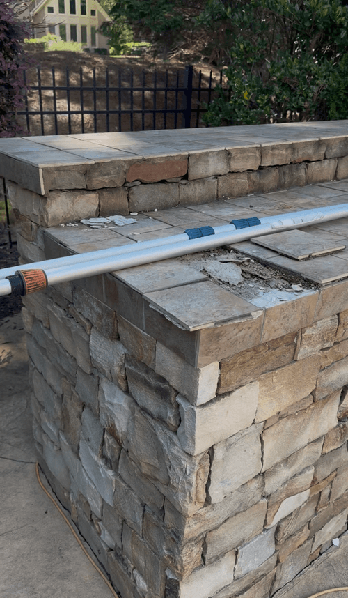 Outdoor kitchen counter with cracked and missing tile before repair