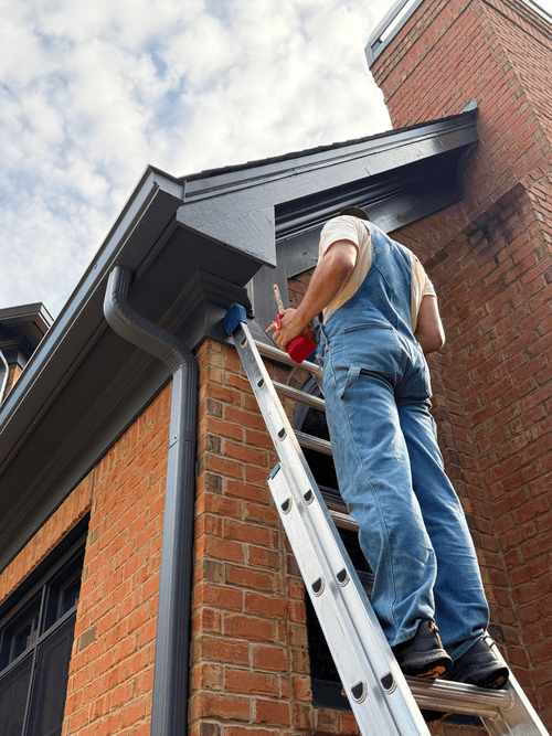 Cutting in the final coat of exterior trim paint on the chimney fascia