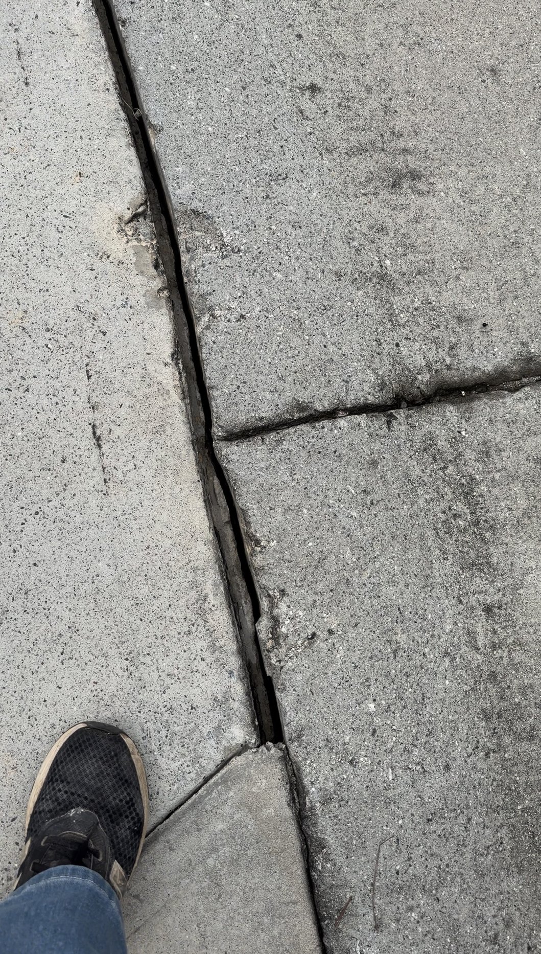 Driveway joint open wide with broken edges at the slab intersection