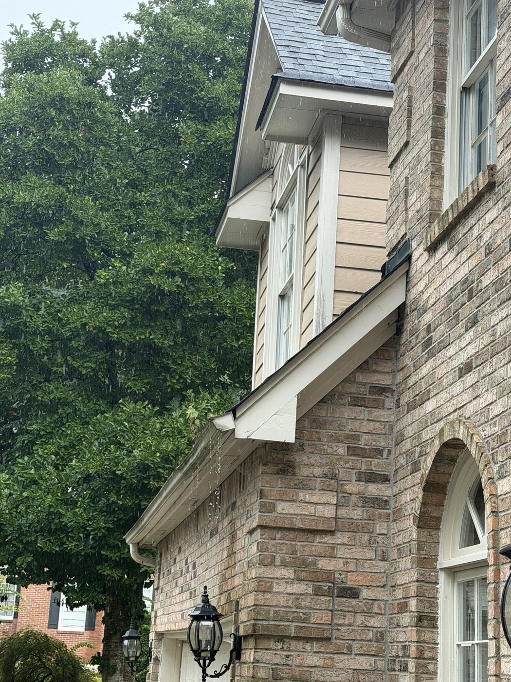 Gutters overflowing in the rain at the front of the house