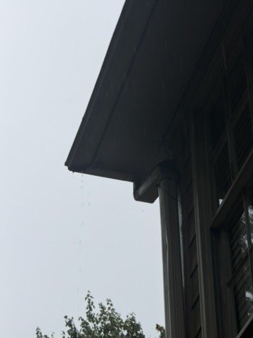 Gutter dripping at a downspout outlet in the rain