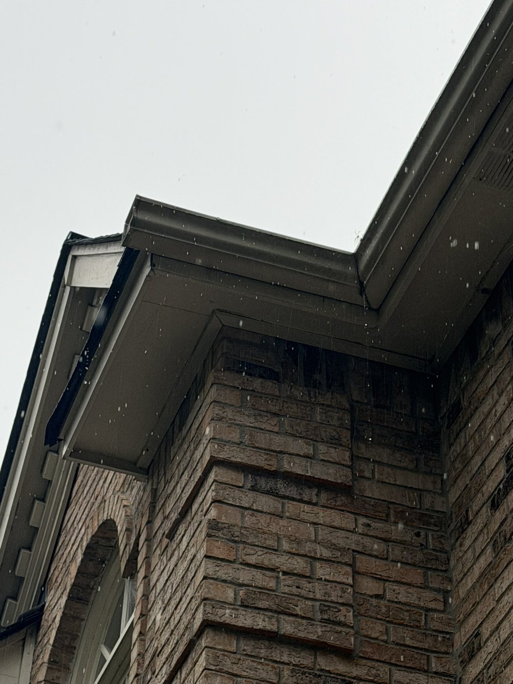 Water running down the brick below the gutter corner