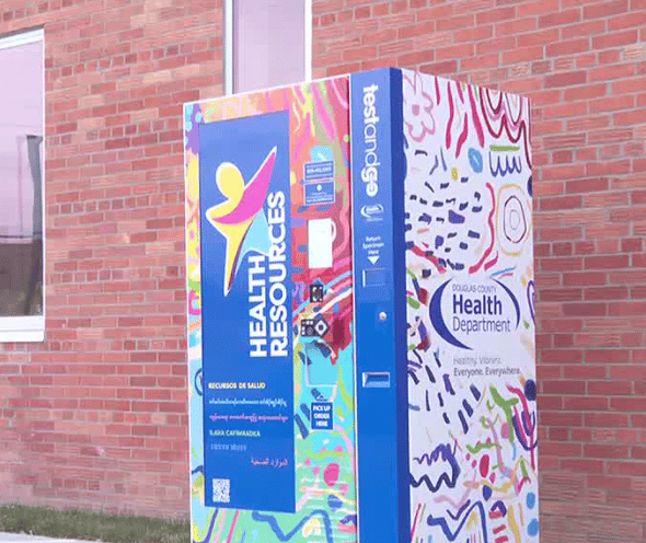 Colorfully painted health resource vending machine outside a brick building with Douglas County Health Department logo.